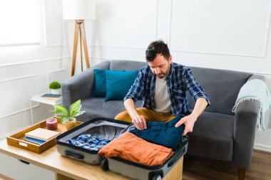 Organize Kafkasyalı adam evinde bavuluna giysilerini yerleştiriyor ve seyahate ya da tatile çıkmaya hazırlanıyor.