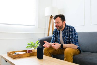 Neşeli çekici bir adam, hoparlörüne oturma odasında müzik dinlemesi için ses komutu veriyor.