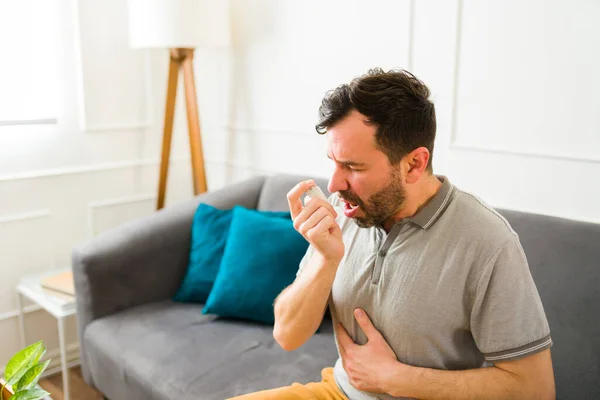 因为哮喘发作和呼吸困难 生病的高加索男人在家里用吸入器 — 图库照片