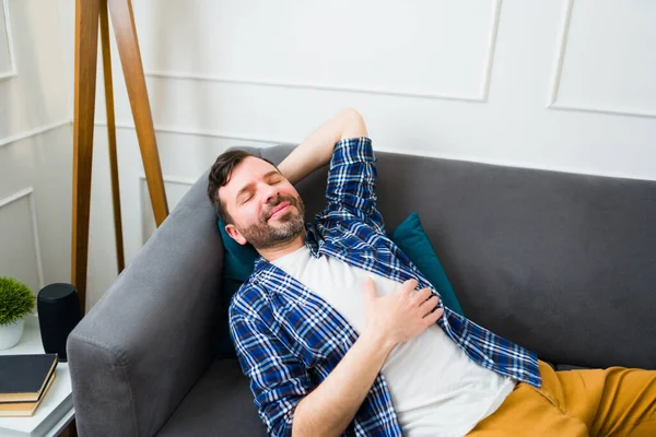 リラックスした白人男性リラックスし 満足と幸せを感じながらソファの上で彼の目を閉じます — ストック写真