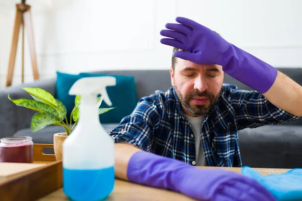 厌倦了30多岁 戴着手套 在打扫房子和做家务活后感到精疲力竭的有魅力的男人 — 图库照片