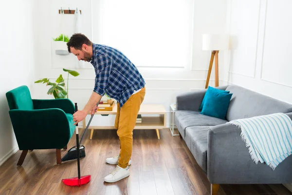 一个三十多岁的负责任的高加索人 用扫帚清扫客厅地板和打扫房子 — 图库照片