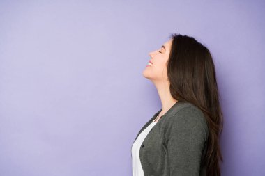 Stüdyonun arka planında 30 'lu yaşlarda neşeli bir kadının mutlu ve rahat bir şekilde gözlerini kapatması. 