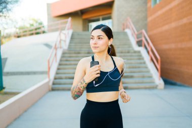 Kulaklıkla müzik dinlerken açık havada koşan güzel İspanyol bir kadın. 