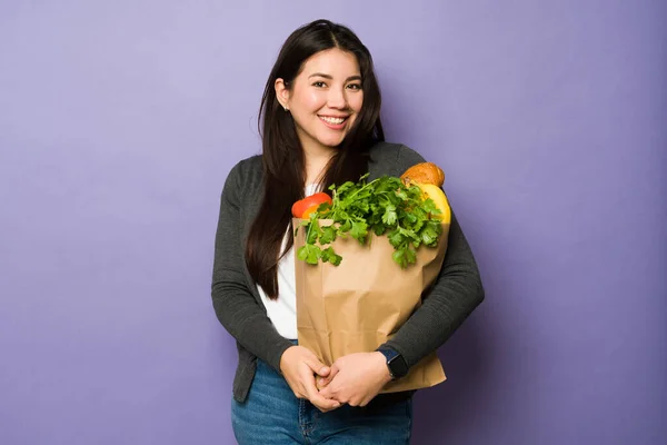 野菜と一緒に食料品袋を持って笑顔の美しい若い女性の肖像画幸せそうに見える — ストック写真