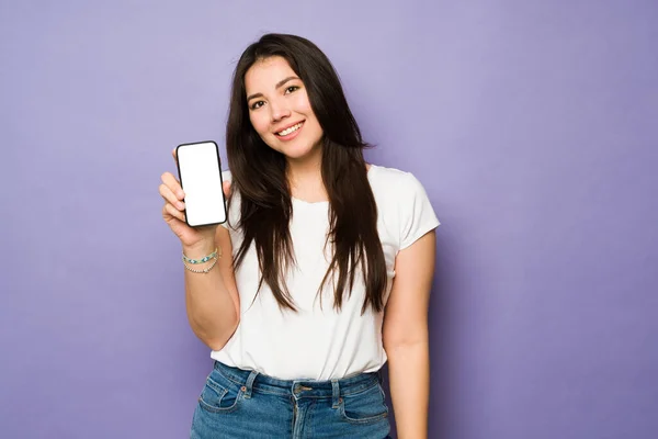 在发短信或使用社交媒体以及眼神交流时 快乐的年轻女性展示她的智能手机屏幕 — 图库照片