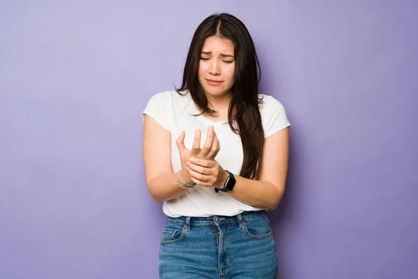 悲伤的高加索女人 患有关节炎 在紫色的背景下痛苦地揉搓着双手 — 图库照片