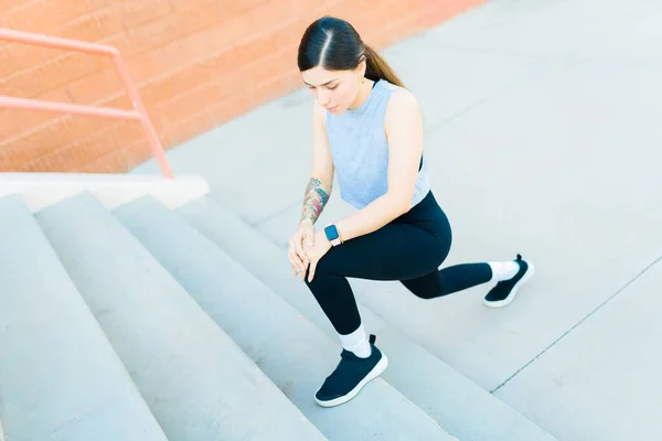 Hispanic beautiful woman with an active lifestyle stretching her legs in the stairs before going on a run outdoors