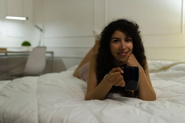 一个快乐而轻松的女人穿着睡衣在床上喝茶时眼神交流的画像 — 图库照片