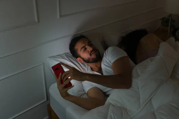 Homem Hispânico Perturbado Mensagens Smartphone Traindo Sua Namorada Enquanto Dormem — Fotografia de Stock