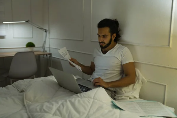 Jovem Ocupado Digitando Seu Laptop Cama Enquanto Trabalhava Casa Tarde — Fotografia de Stock