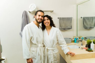 Evde dinlendirici bir sabahta beyaz cübbe giyen güzel bir çiftin portresi.