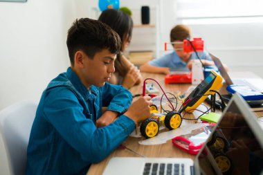 Bir grup ortaokul öğrencisi bir teknoloji projesi yapıyor ve elektronik dersinde robot yapmayı öğreniyorlar.