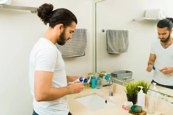 西班牙裔男子把牙膏放进牙刷 准备早上在浴室刷牙 — 图库照片