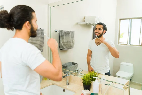 快乐的年轻人微笑着看着浴室的镜子 在早上的例行公事中刷牙 — 图库照片