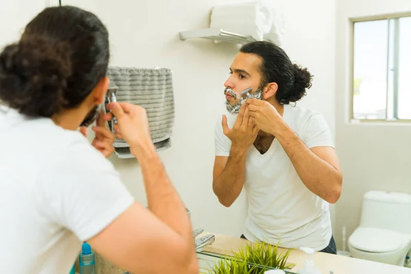 浴室里的英俊男子用剃须刀刮胡子 并使用美容产品 — 图库照片