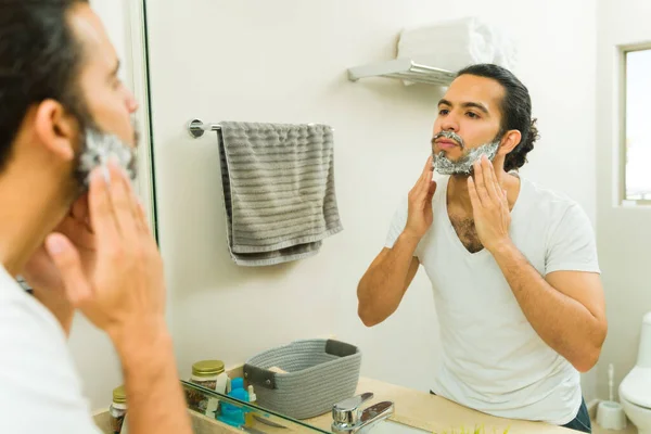 一个有魅力的西班牙男人在梳妆打扮和刮胡子的时候照着浴室的镜子 — 图库照片