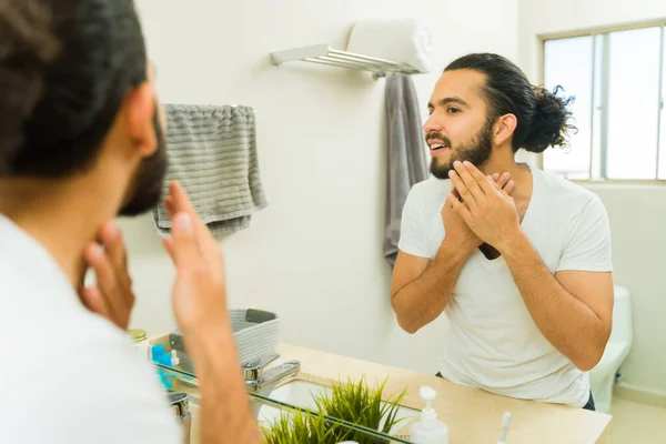 英俊的年轻人在浴室里笑着 对自己的胡子和日常的皮肤护理很开心 — 图库照片