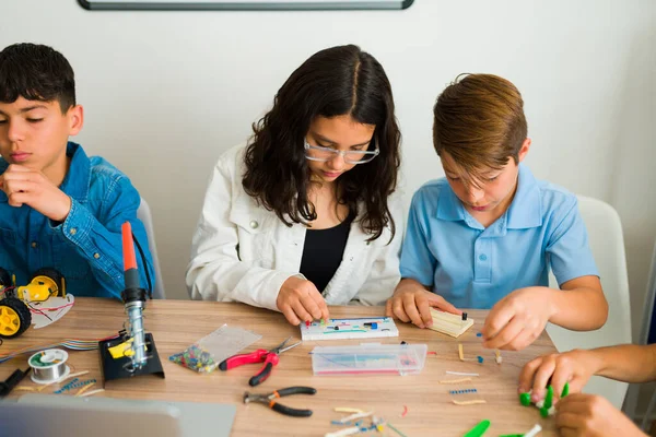 白人の少年とラテン人の少女は クラスプロジェクト中にプロトタイプを構築しながら 電子回路がどのように機能するかを学ぶ — ストック写真