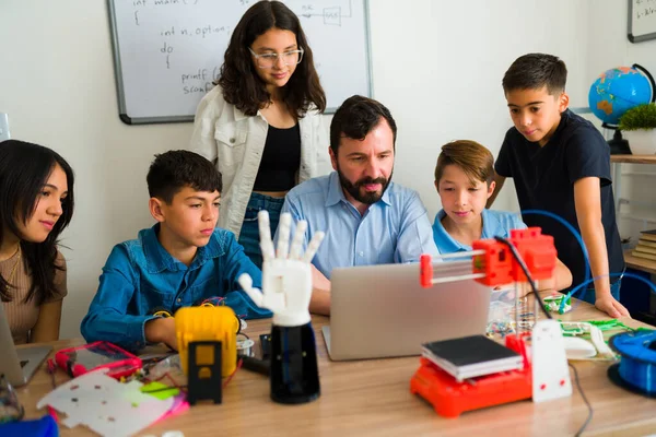 ヒスパニック系の男性教師と中学校の学生は ロボットクラスでロボットのプロトタイプを構築しながらコーディングやプログラミング — ストック写真