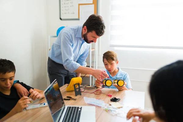 10代の学生が教育課程の間にプログラミングしながら電子プロトタイプを構築するのを助けるロボット教師 — ストック写真