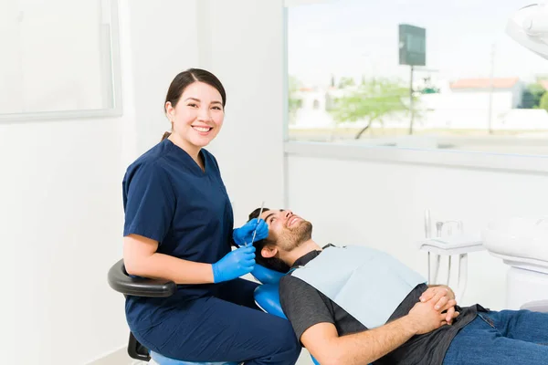 快乐的高加索女牙医 戴着蓝色的刷子和手套 随时准备检查病人 — 图库照片