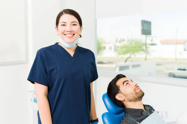 在对病人进行了牙齿清洁和检查后 快乐的女人身穿洗涤剂和面罩 看上去很开心 — 图库照片
