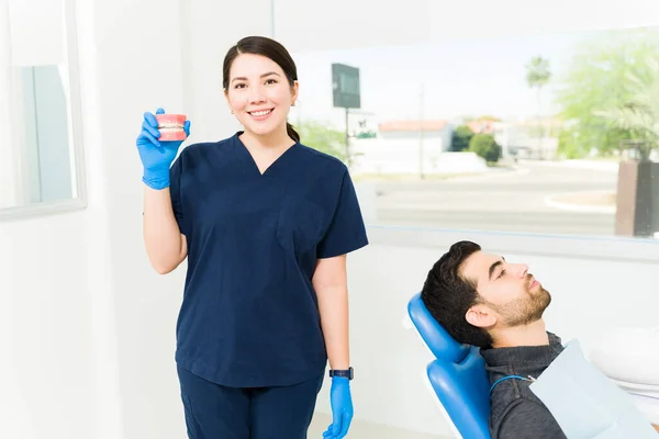 Piękna Biała Kobieta Dentysta Niebieskim Fartuchu Pokazuje Protezę Lub Sztuczne — Zdjęcie stockowe