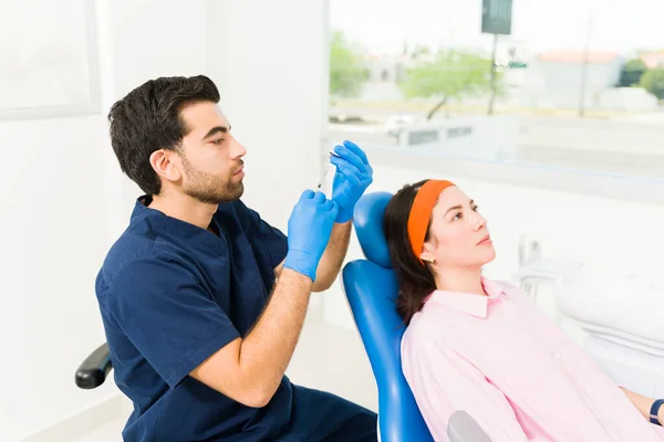 在美容院为一位高加索妇女患者准备肉毒杆菌毒素注射剂时 他的恐慌医生很有吸引力 — 图库照片