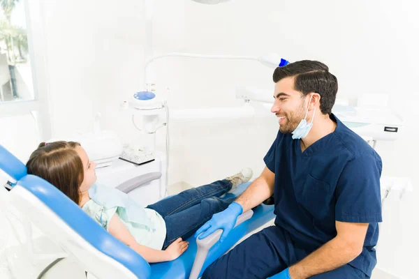 快乐的男婴牙医微笑着与一位年轻的女病人进行了牙科检查后谈话 — 图库照片