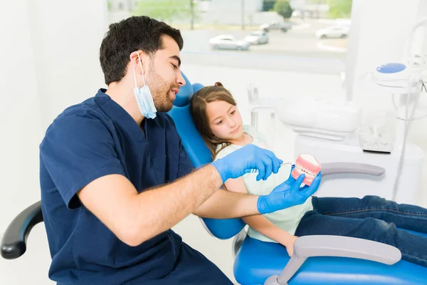 Młody Dentysta Dziecięcy Pokazujący Wyjaśniający Jak Myć Zęby Protezą Podstawowemu — Zdjęcie stockowe