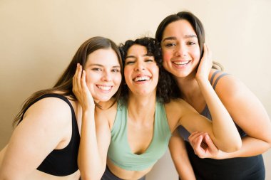 Güzel, çeşitli bayan arkadaşlar birlikte egzersiz yaparken sarılıp gülüyorlar. 