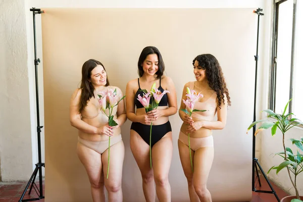 Atrakcyjne Zróżnicowane Kobiece Kobiety Bieliźnie Trzymające Kwiaty Studio Dużą Pozytywnością — Zdjęcie stockowe