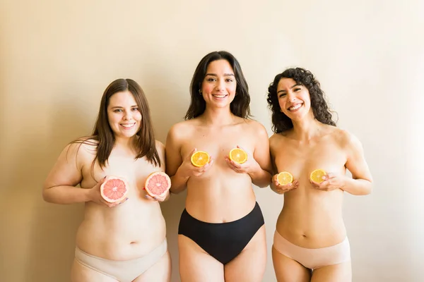 Trzy Zróżnicowane Młode Kobiety Gołą Klatką Piersiową Zakładają Pomarańczowe Owoce — Zdjęcie stockowe