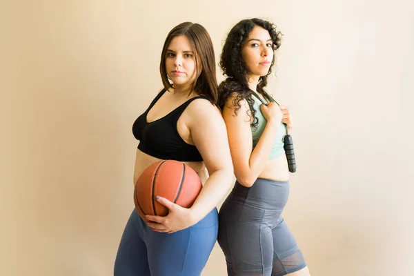 Caucasian plus size woman and latin young woman ready to play basketball and jumping rope together for workout exercises