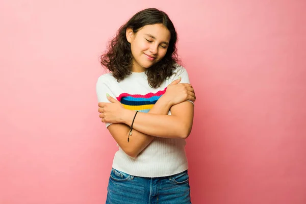 美しいですティーンラテン女の子抱擁自分自身と感じ自己愛と自己尊重しながら見ますリラックスしたピンクのスタジオの背景 — ストック写真