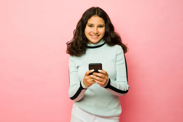 快乐的13岁少女在智能手机上使用社交媒体和发短信时微笑着 — 图库照片
