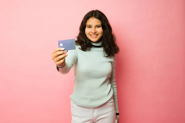 他惊慌失措的少女展示了她的第一张信用卡 并在粉色背景下购物时支付了钱 — 图库照片