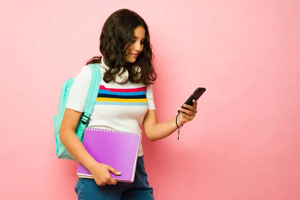 上初中时 十几岁的女生背着背包和书本 用智能手机发短信 — 图库照片