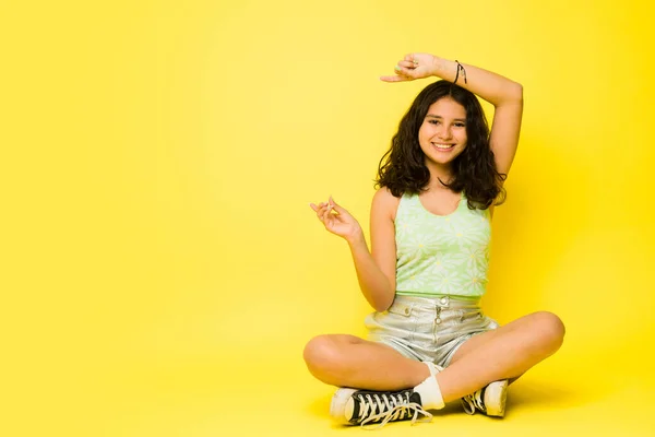 13岁的小女孩坐在演播室里开心地指着一个黄色的版面广告 — 图库照片
