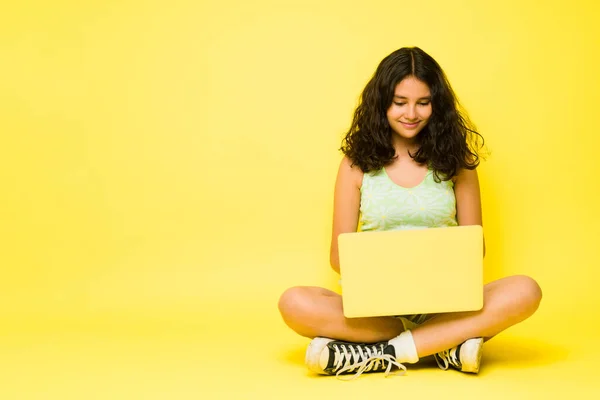 13岁的拉丁女孩 卷发在笔记本电脑上打字 在一个黄色的复制空间旁边上网购物或做作业 — 图库照片
