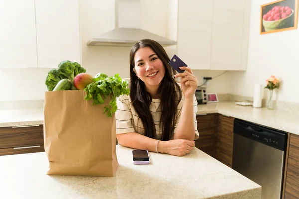 在超市买了食品杂货和有机食品后 厨房里的白人快乐女人拿出她的新信用卡 — 图库照片
