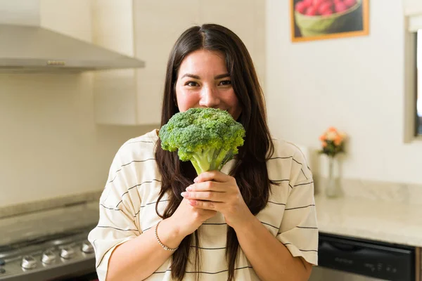 有魅力的素食主义者女人一边与人眼神交流 一边微笑 同时展示着准备烹调健康食品的绿色蔬菜花椰菜 — 图库照片