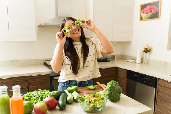 在厨房里一边用有机蔬菜做饭一边做素食菜谱的有趣而兴奋的女人 — 图库照片