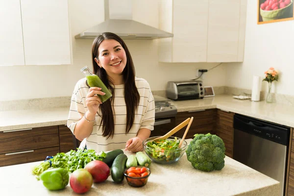 迷人的素食主义者微笑着喝着绿果汁 用有机蔬菜烹调健康的菜谱 — 图库照片