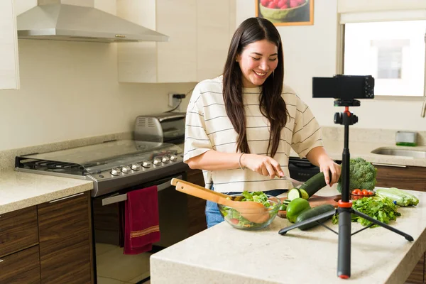 快乐的女性影响者在拍摄烹饪视频的同时制作素食菜谱 并在厨房里用相机拍摄 — 图库照片