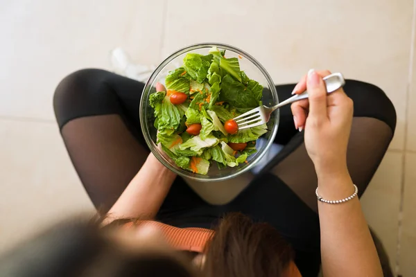 健康的な菜食生活を送る女性のトップビュー運動後に緑の有機サラダを食べる — ストック写真