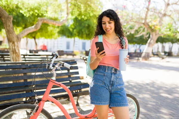 彼女の20代の飲酒コーヒーで魅力的なヒスパニック女性の肖像画は 通勤のために公園で彼女の自転車に乗る使用中 — ストック写真