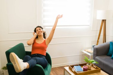 Heyecanlı genç bir kadın boş zamanlarında kulaklıkla müzik dinlerken dinleniyor ve dinleniyor.