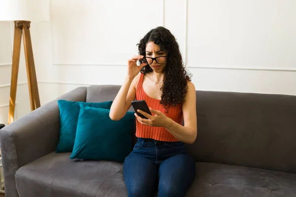 漂亮的年轻女子在客厅里戴眼镜 在使用智能手机和发短信时视力或视力有问题 — 图库照片